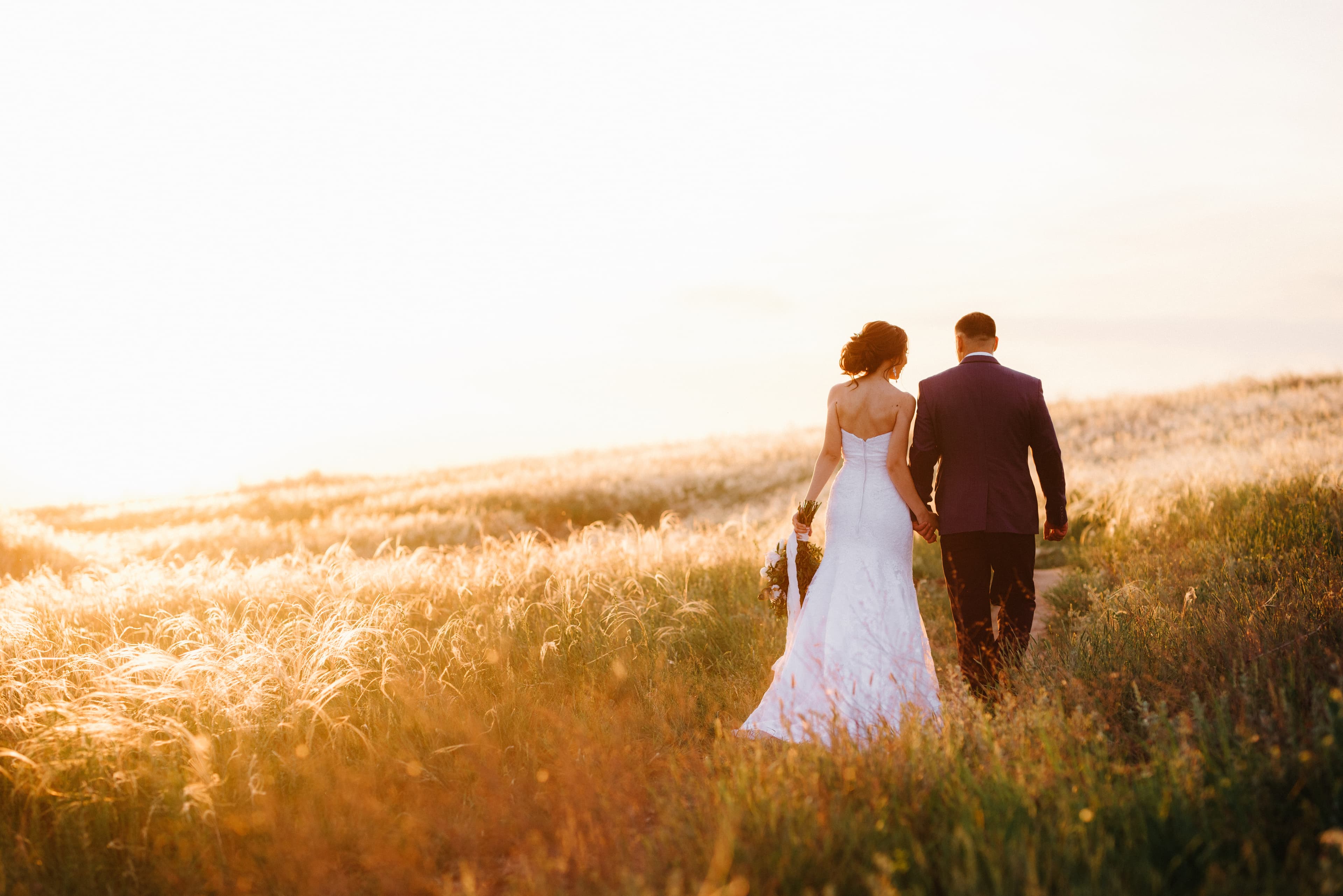 Pareja de novios caminando en un campo al atardecer